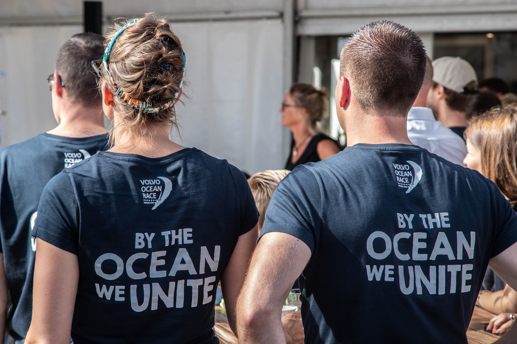 Vrijwilligers dragen Volvo Ocean Race-shirts met de tekst By the ocean we unite