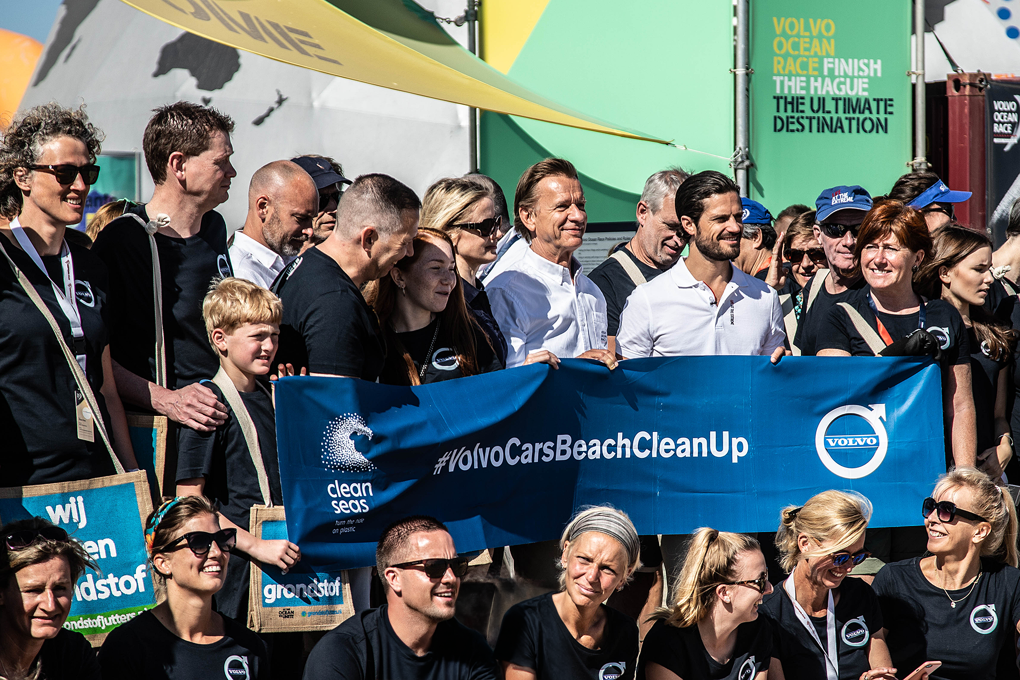 Håkan Samuelsson en prins Carl Philip van Zweden met de vrijwilligers achter het Volvo Cars Beach Clean-Up-spandoek